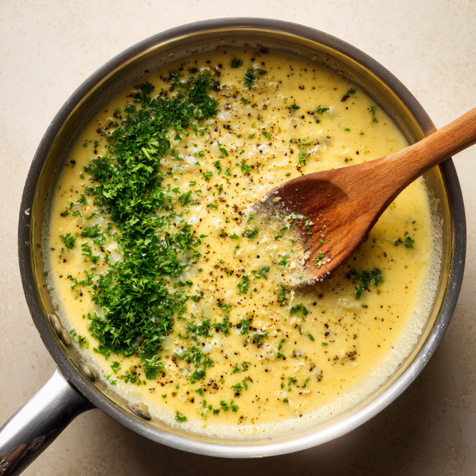 Creamy lemon garlic sauce being stirred with a wooden spoon in a skillet
