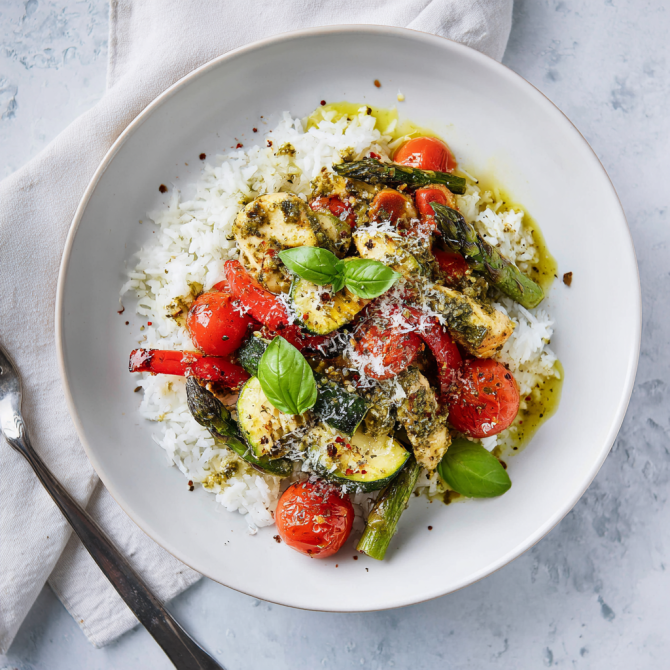 Serving of pesto chicken and vegetables over pasta with Parmesan