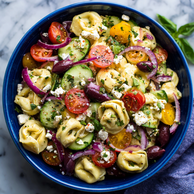 Colorful tortellini pasta salad with cherry tomatoes, cucumbers, olives, and feta